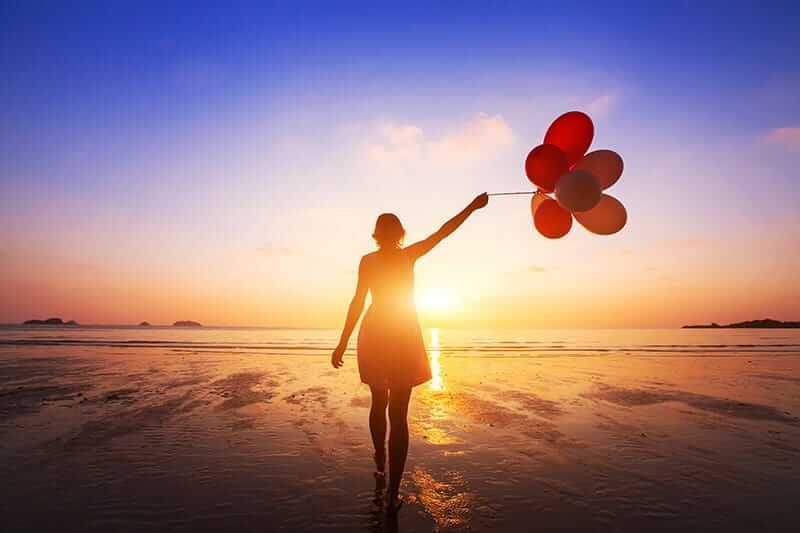 A woman on the beach celebrates her success after somatic therapy